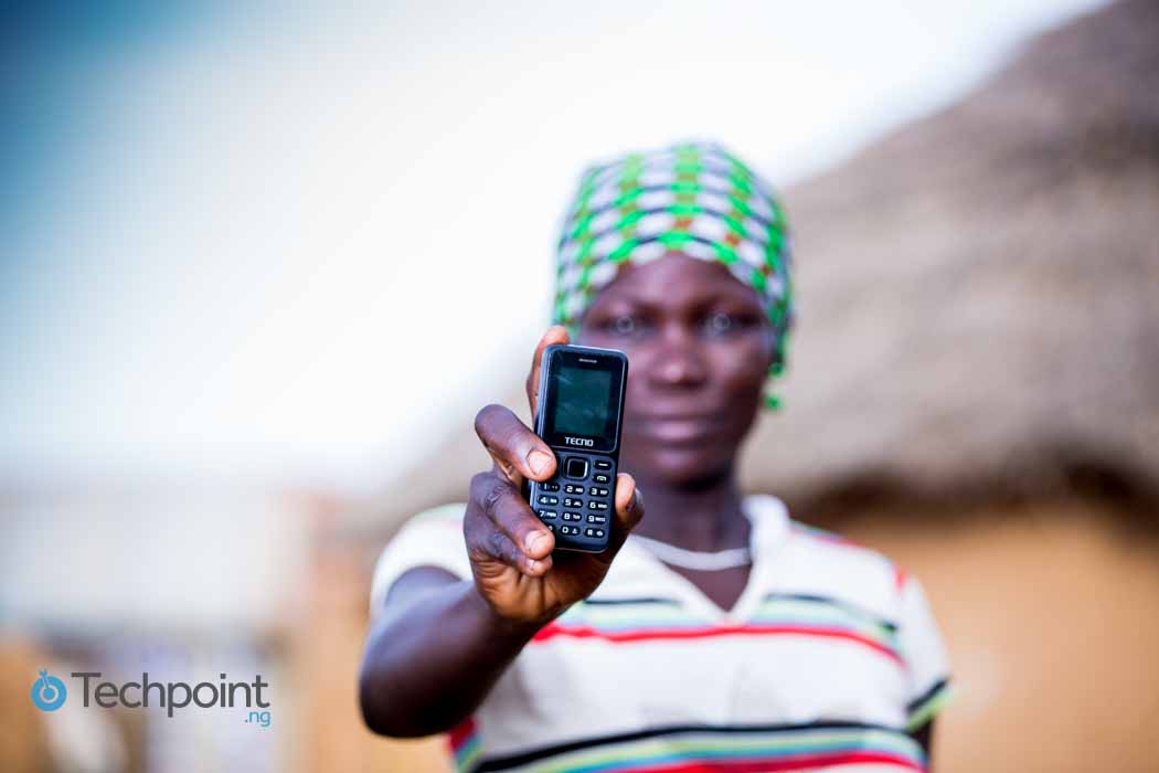 Person holding a feature phone showing Anansi AI accessibility